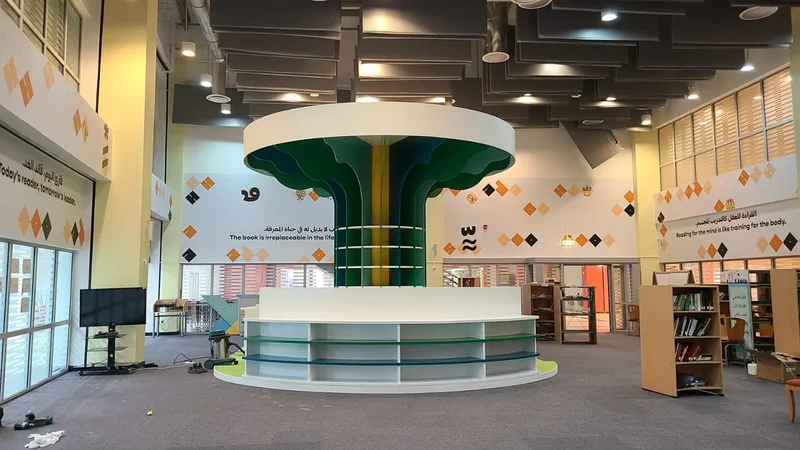 Long library counter positioned beside the large tree-form bookshelf installation.