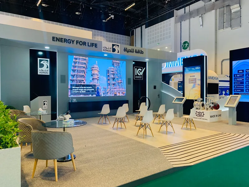 Custom fabricated white scenic walls and presentation area forming the ADNOC ADIPEC exhibition environmen