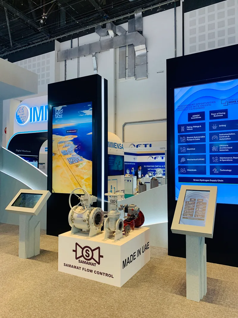 ADNOC exhibition stand featuring painted MDF scenic structures and large integrated digital display screens