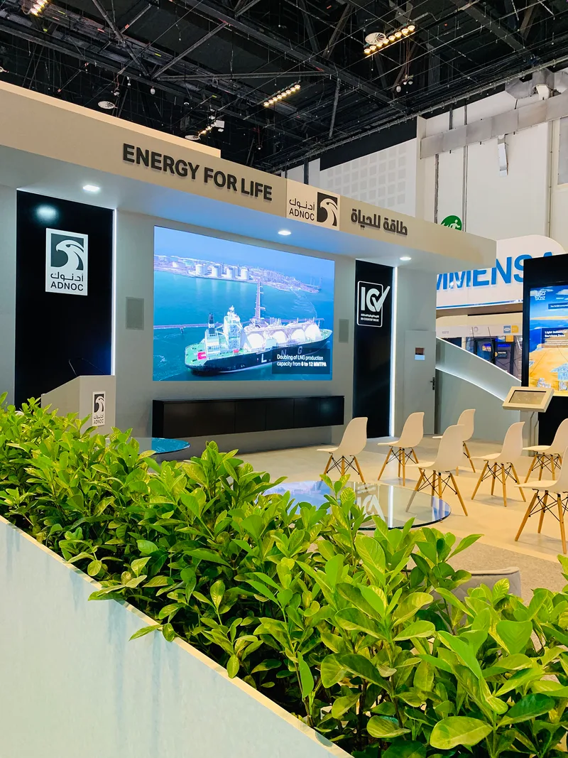 ADNOC branded scenic architecture combining painted MDF walls, graphics and digital presentation displays