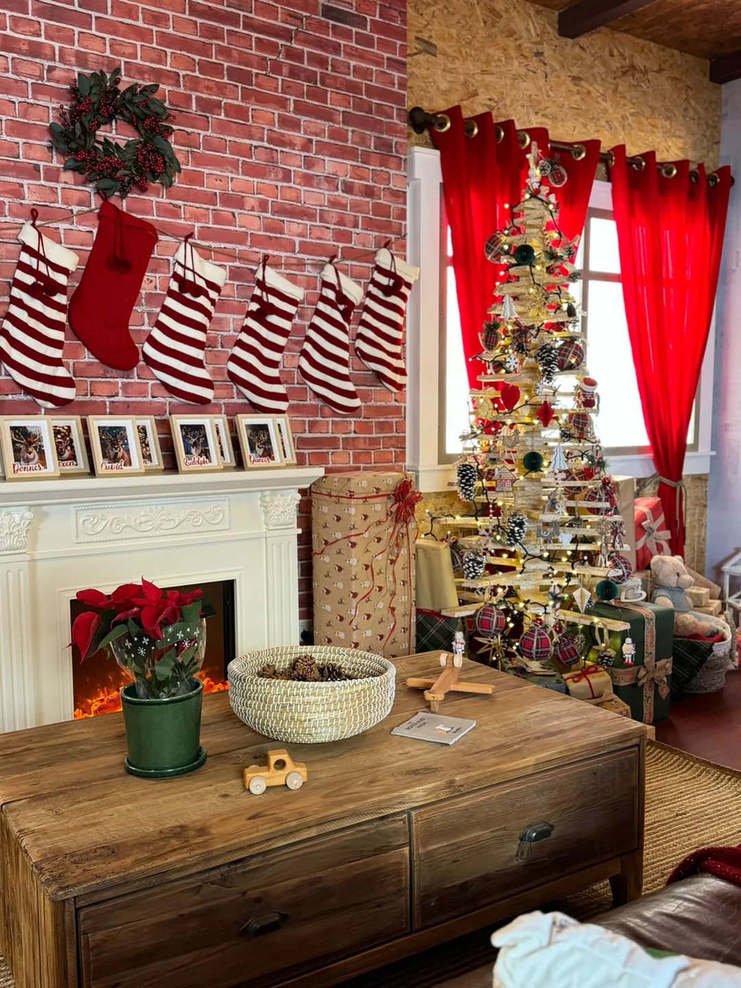 Scenic Christmas tree, wrapped presents and fireplace installation inside the temporary house.
