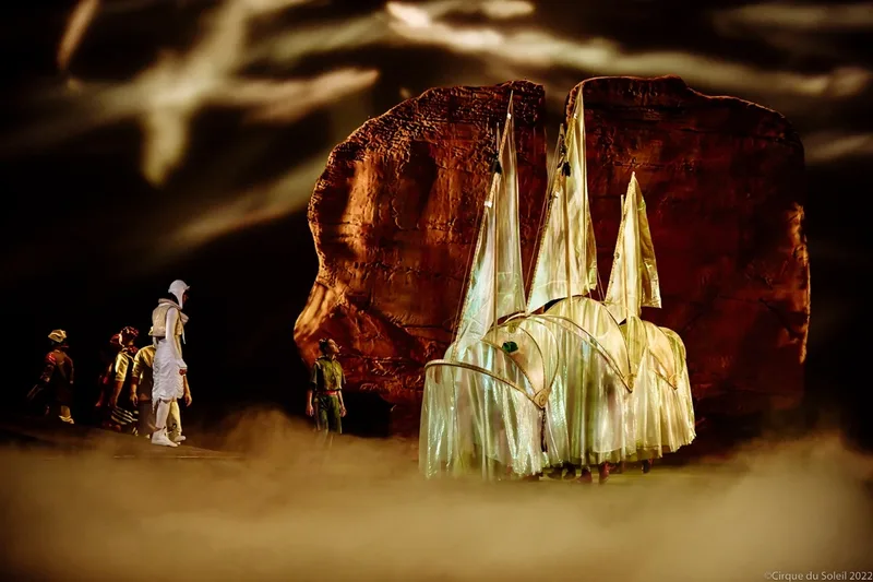 Translucent pointed scenic prop illuminated beside the monumental rock stage environment.