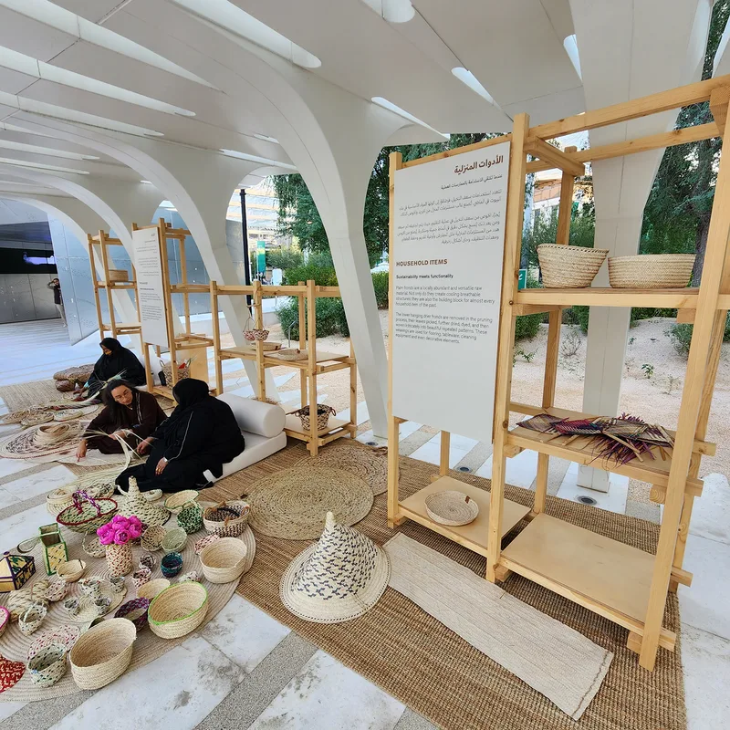 Stained timber shelving displaying woven cultural objects within the UAE Pavilion installation.