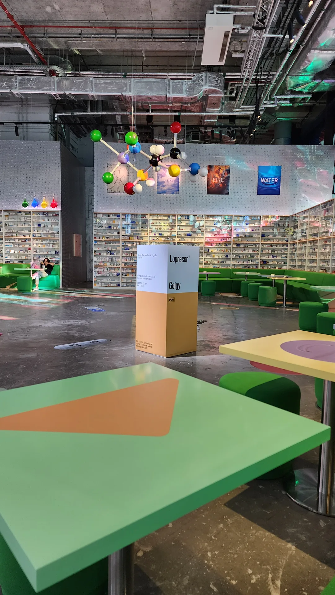 Custom upholstered seating and tables integrated into the Prada Mode scenic layout.
