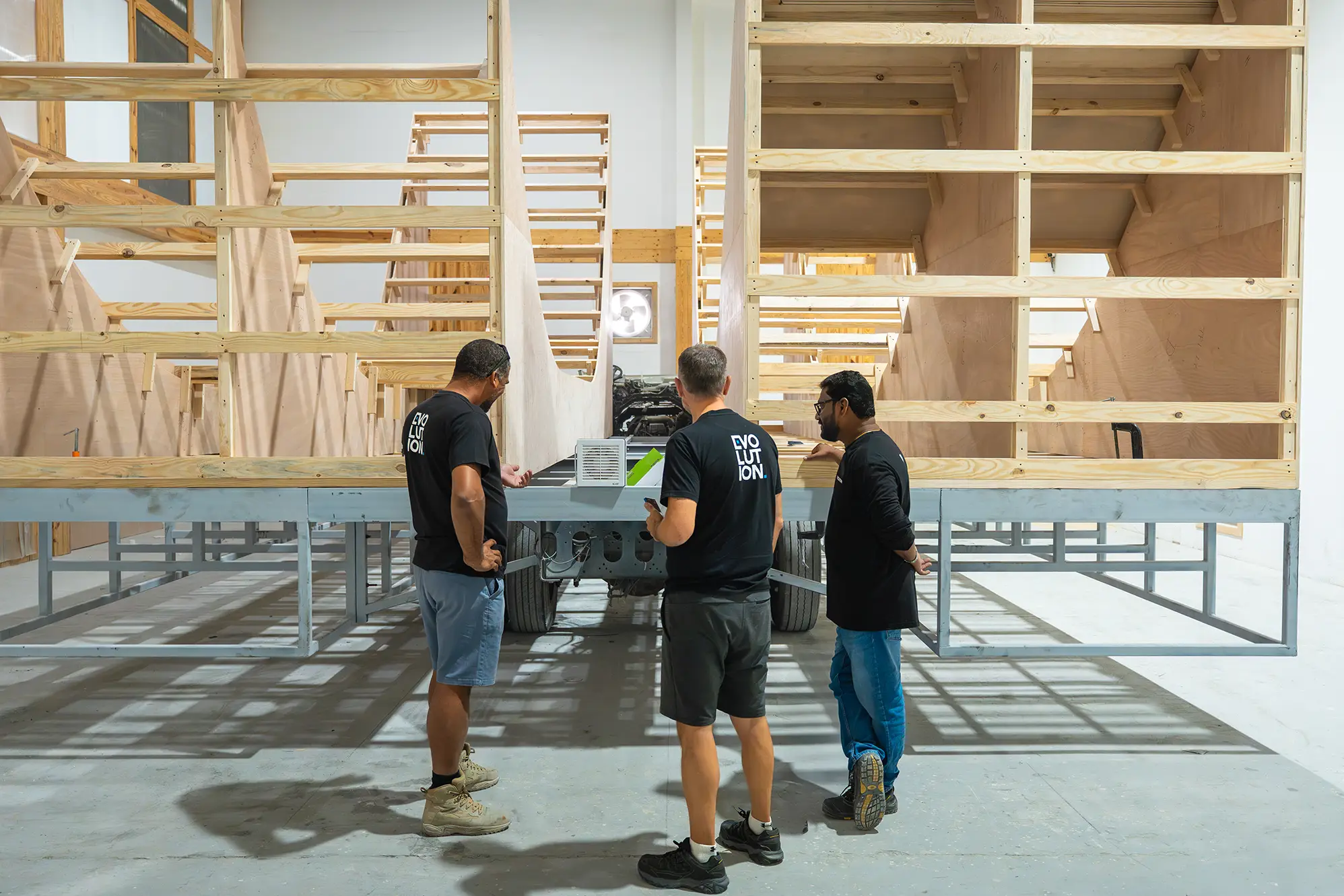 Evolution Scenic team reviewing technical drawings beside a partially assembled scenic structure
