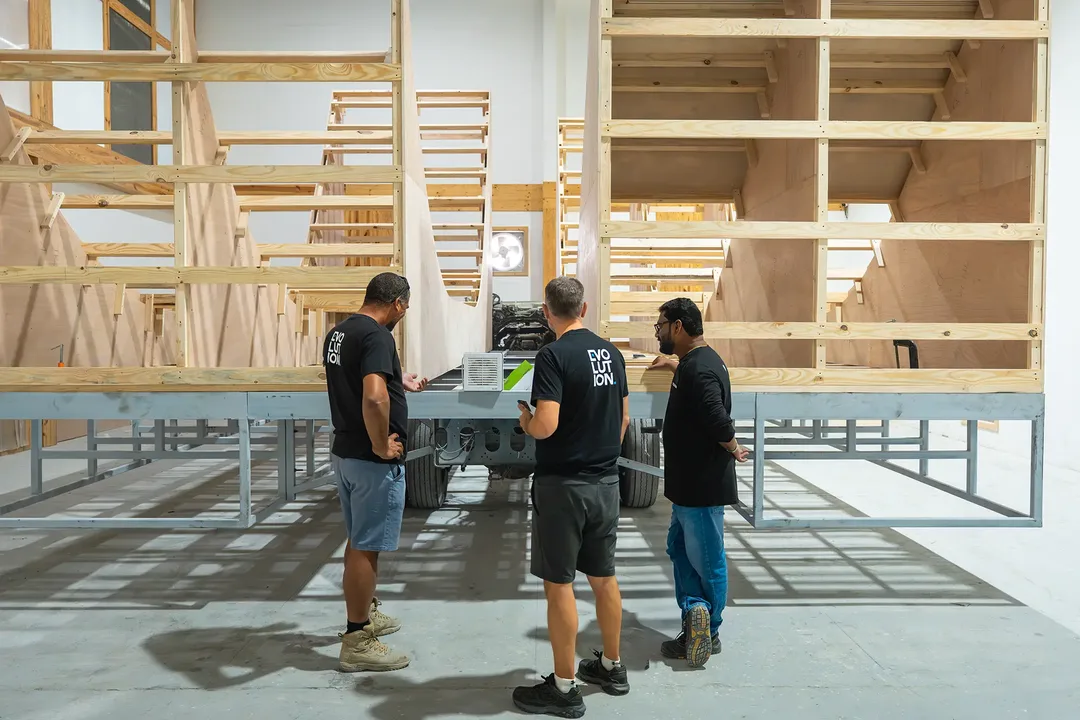 Evolution Scenic team reviewing technical drawings beside a partially assembled scenic structure
