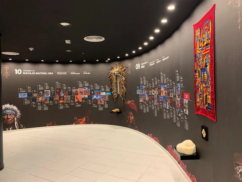 Timber-framed black exhibition walls with integrated graphics and cultural display plinths.