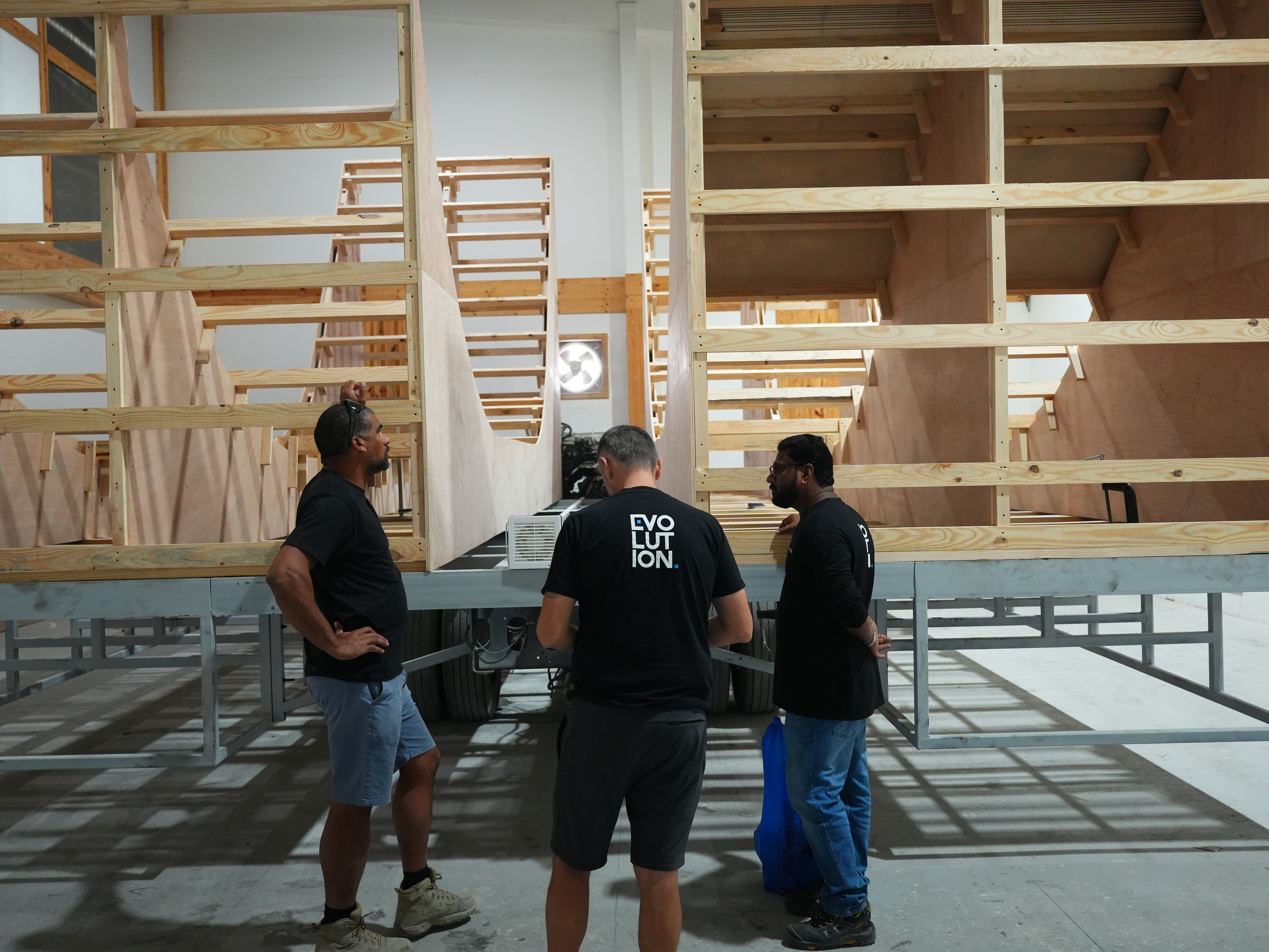 Evolution Scenic team reviewing technical drawings beside a partially fabricated scenic structure.
