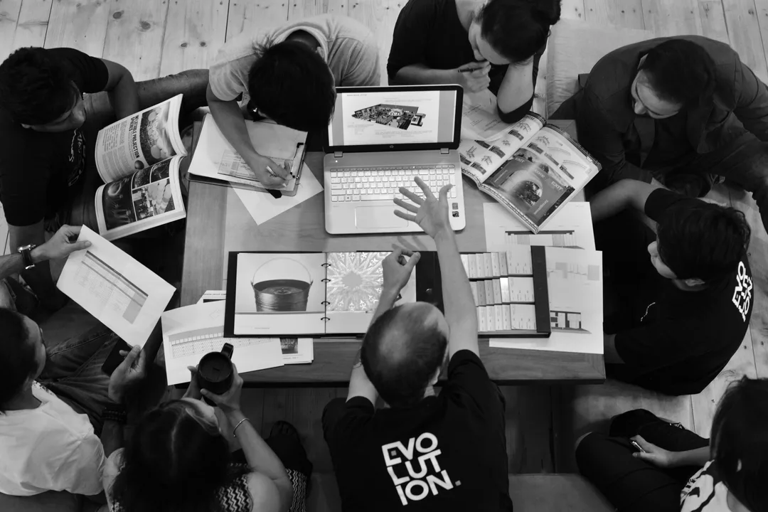 Fabrication specialists studying scenic concept objectives alongside technical drawings and material samples.
