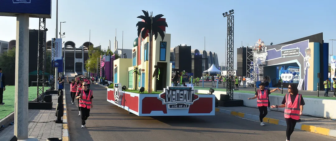 Image desEvolution Scenic purple Mansour parade float with illuminated gateway and rock-effect base.cription