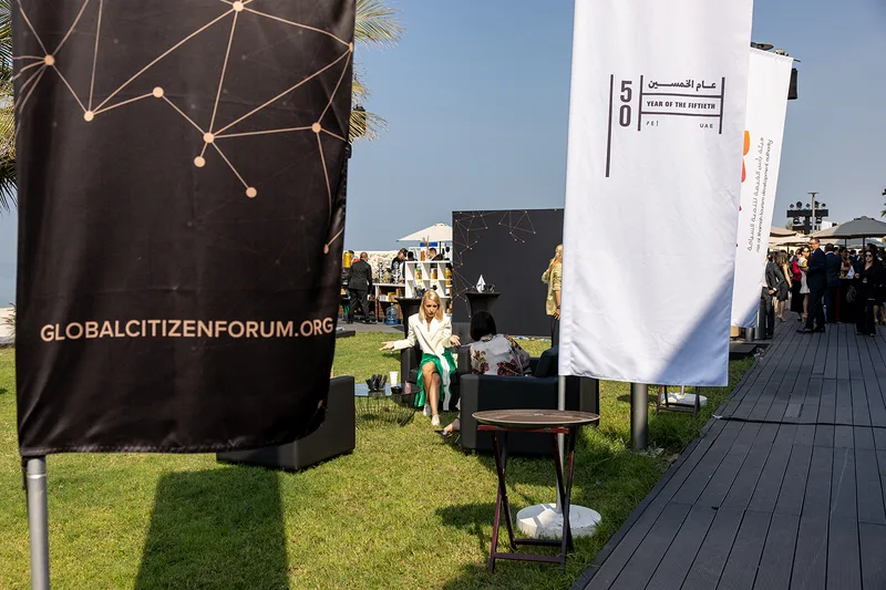 Global Citizen Forum branded fabric flags installed throughout the outdoor hospitality and networking environment.