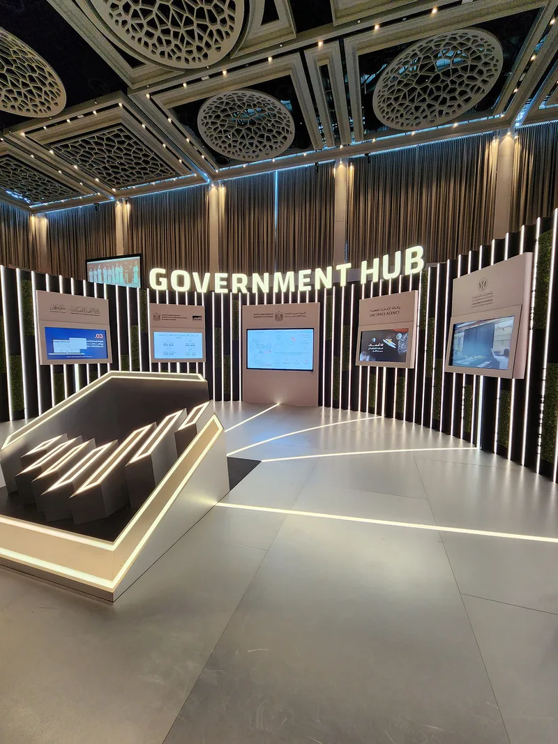 Government Hub scenic wall featuring illuminated vertical fins and recessed digital displays.