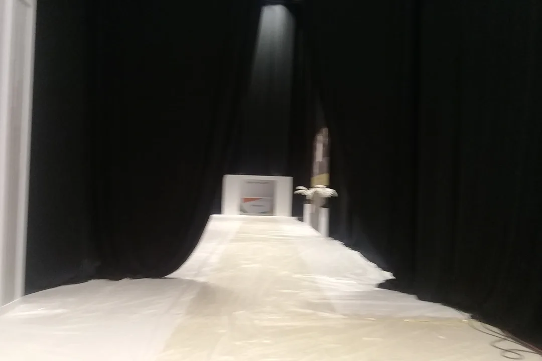 Black drape installation comparing flat hanging fabric with fuller pleated masking
