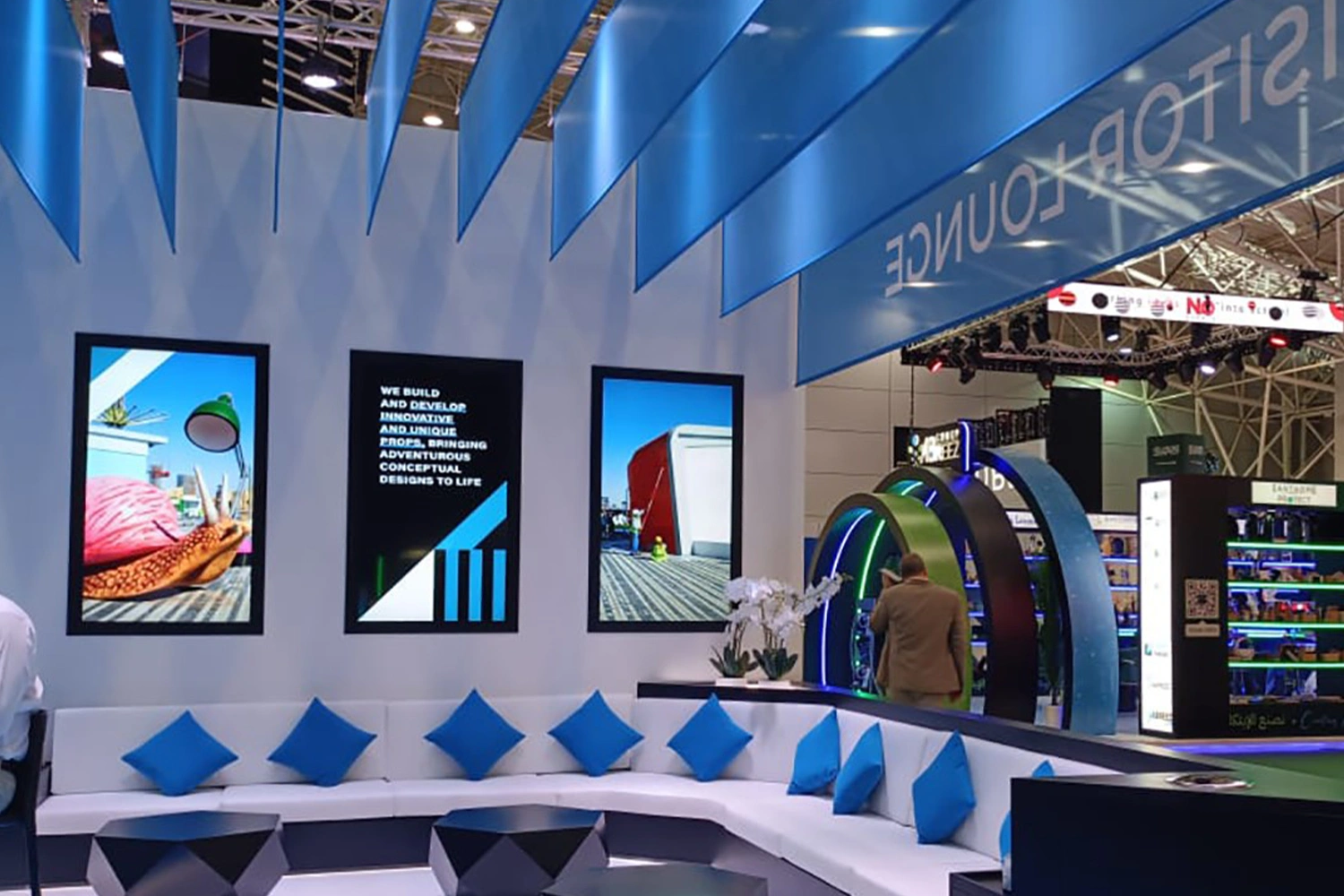 Modular white scenic wall construction surrounding fitted lounge seating and display screens.