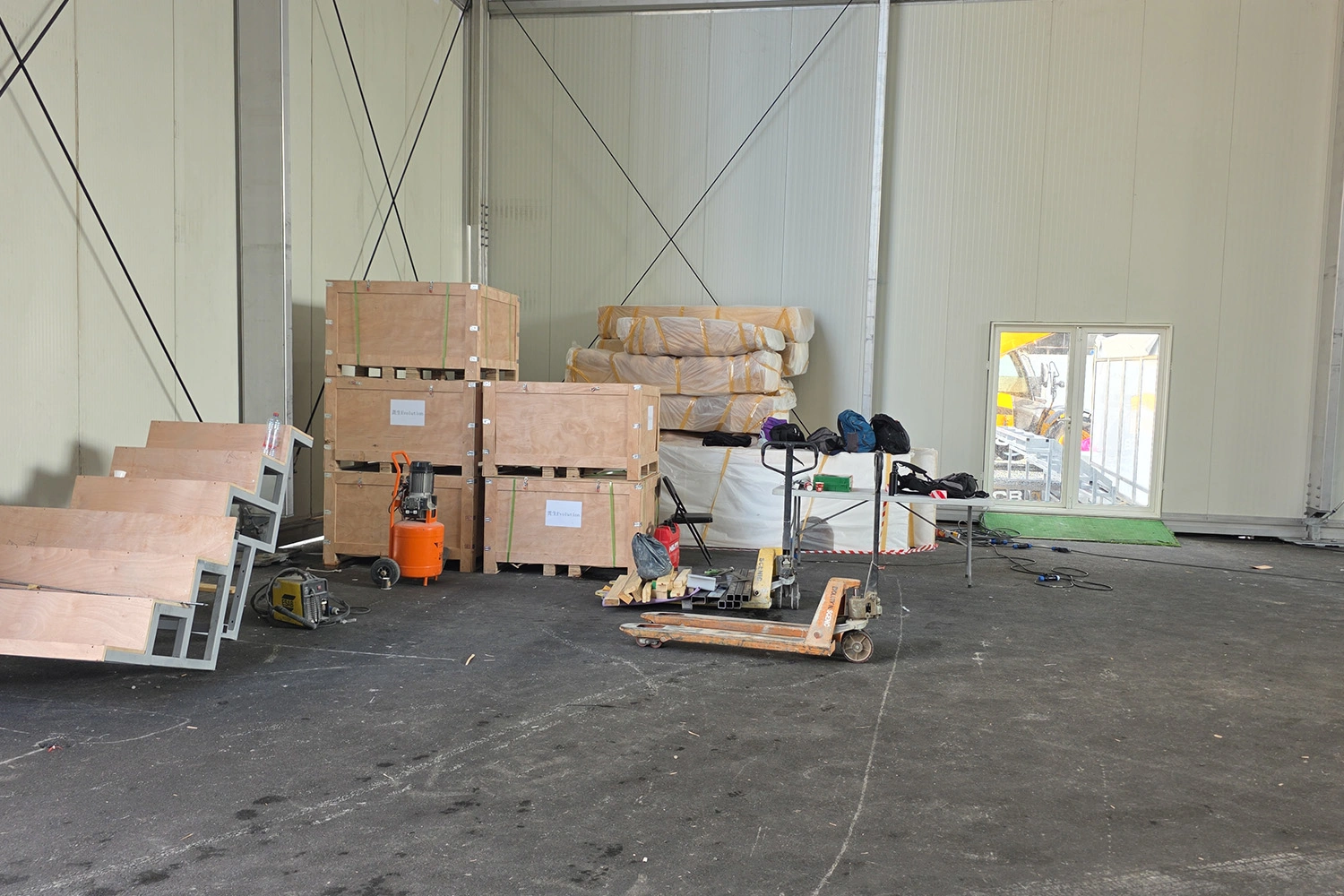 Scenic crates and fabricated modules staged beside a loading dock with handling equipment ready for unloading.
