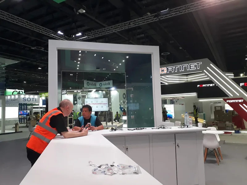 Custom HPE exhibition architecture combining glazed rooms, scenic walling and integrated lighting.