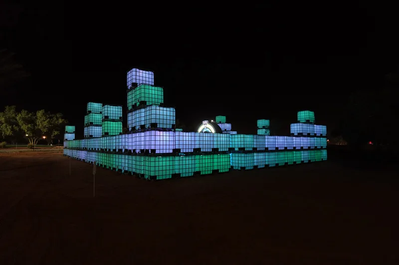 Illuminated IBC container maze with stacked modular towers at LIV Golf Riyadh 2025.
