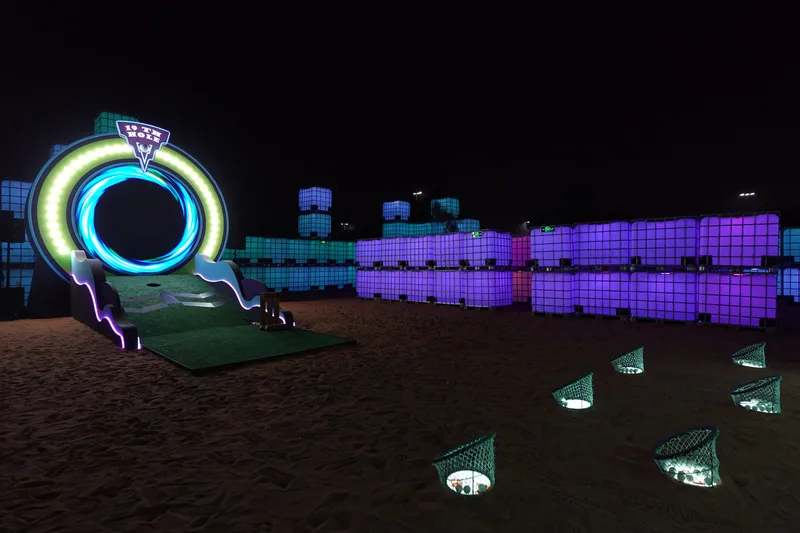 Evolution Scenic nineteenth-hole putting structure with illuminated circular portal and artificial grass.