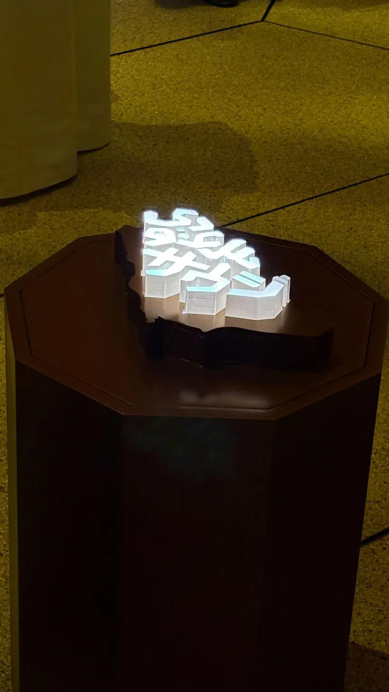 Illuminated poured-resin emblem integrated within the custom faceted scenic structure.
