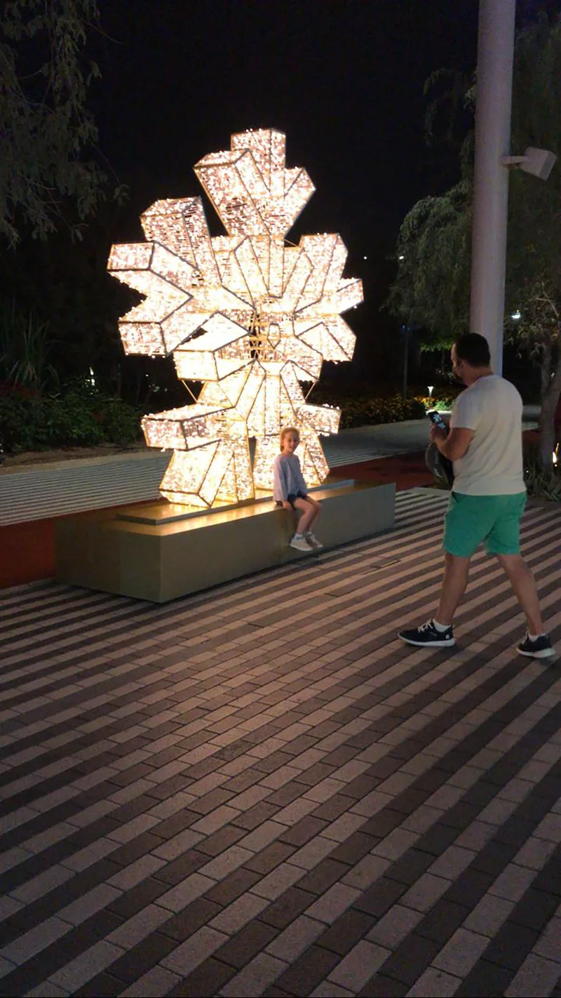 Refurbished illuminated snowflake sculpture positioned on a large public-realm scenic base.