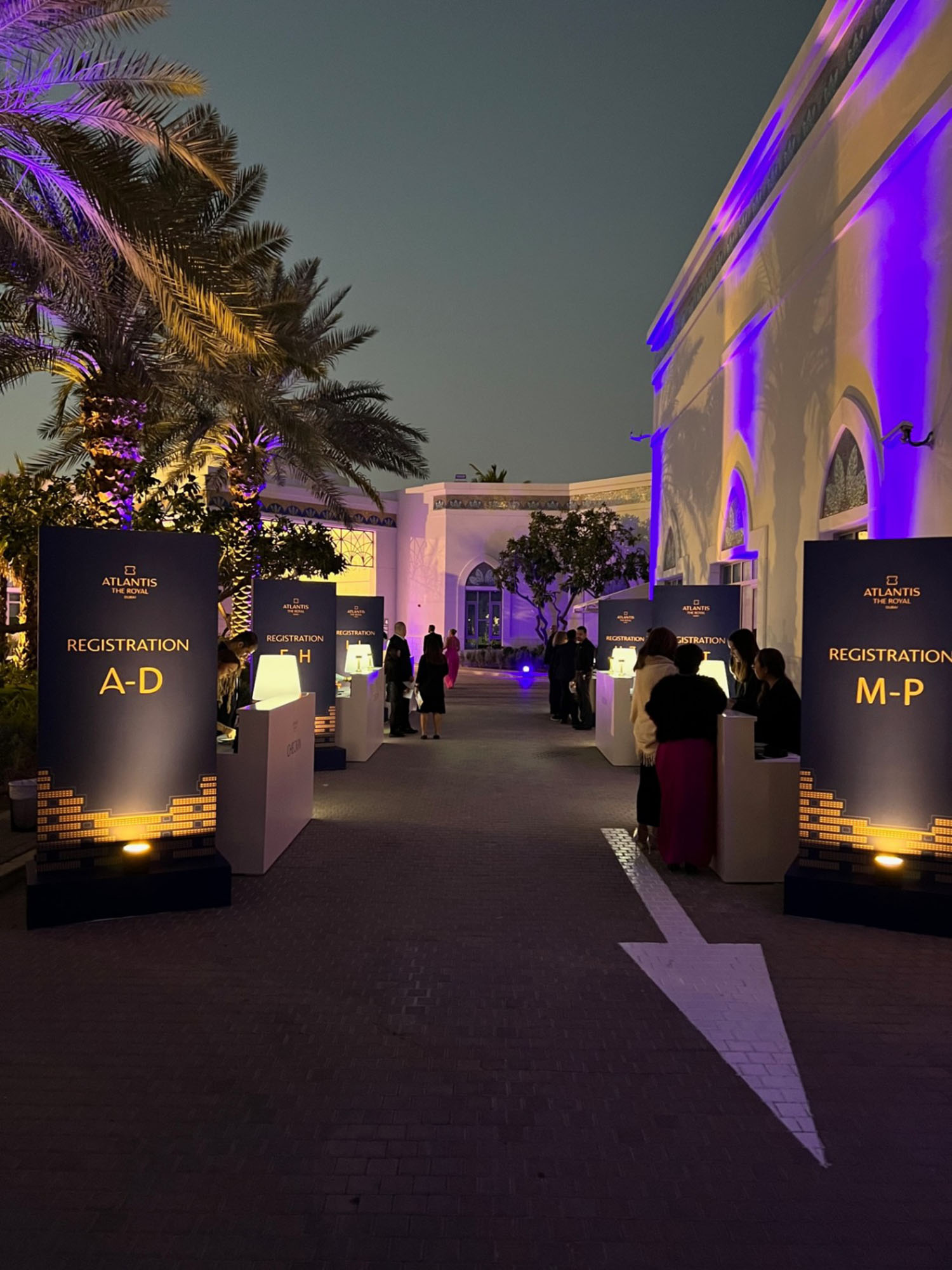 Illuminated wayfinding elements defining circulation routes across the Atlantis outdoor setting.