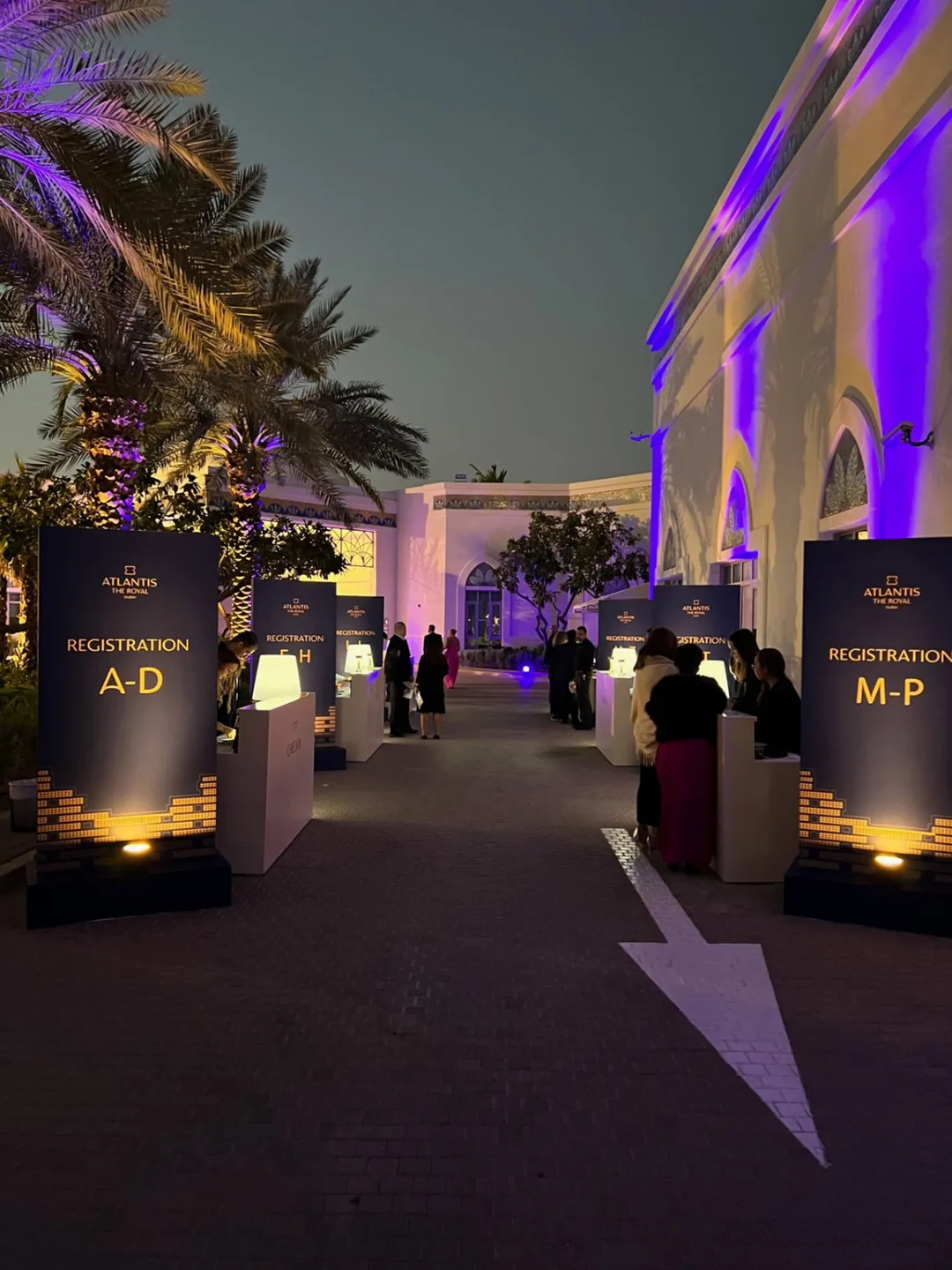 Illuminated wayfinding elements defining circulation routes across the Atlantis outdoor setting.