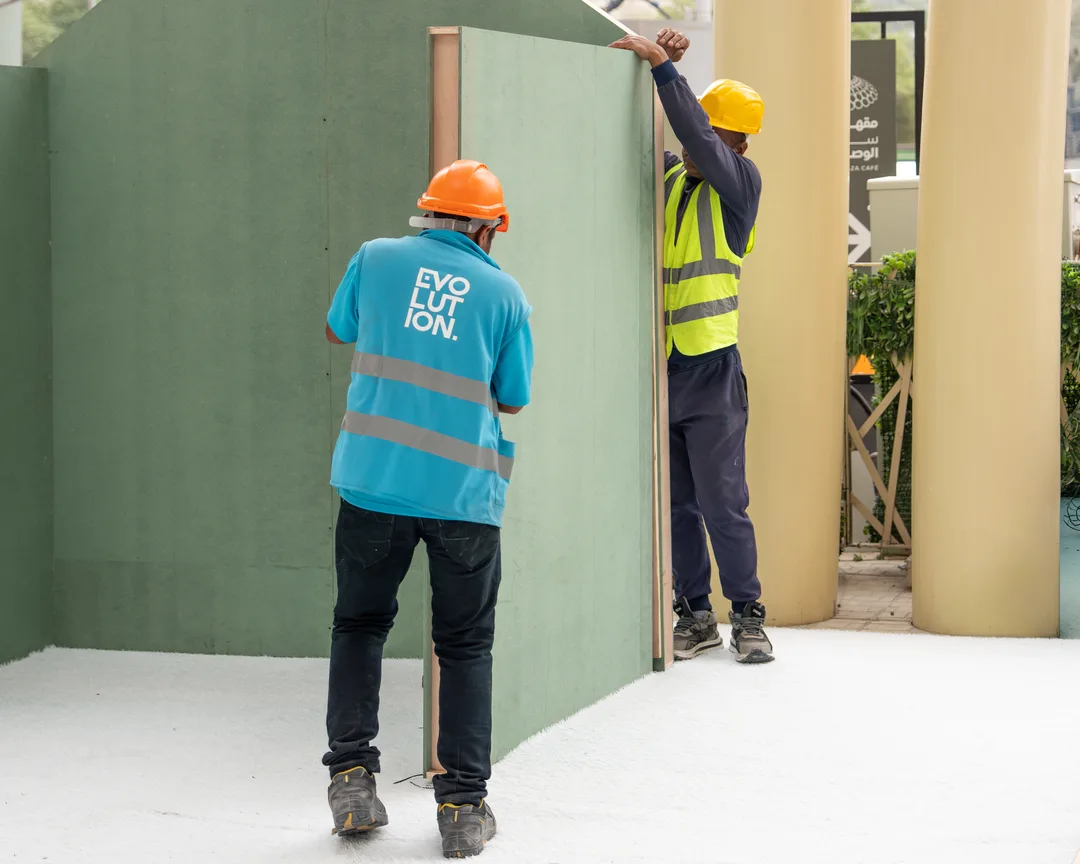 Scenic installers making late adjustments to fabricated exhibition panels and structural connections
