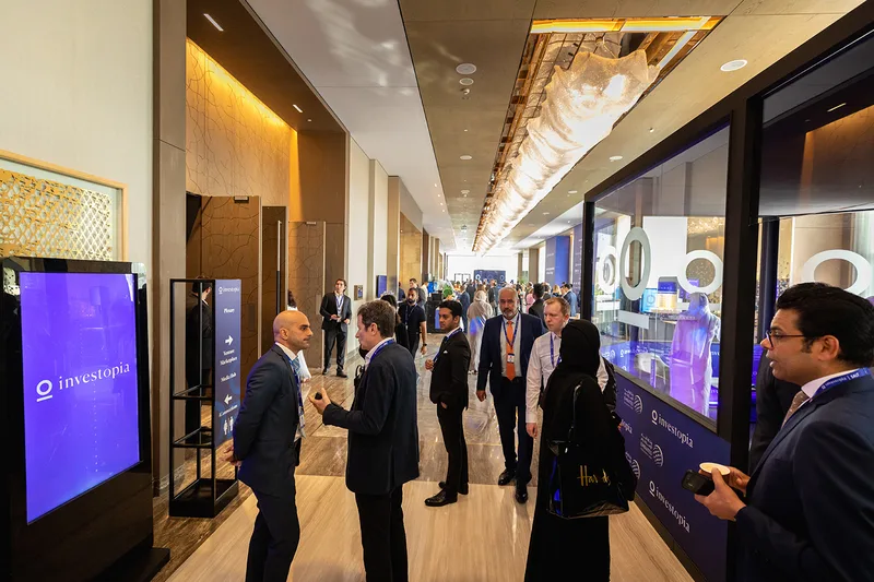 Interactive scenic wall with glazed display sections and illuminated Investopia motifs.