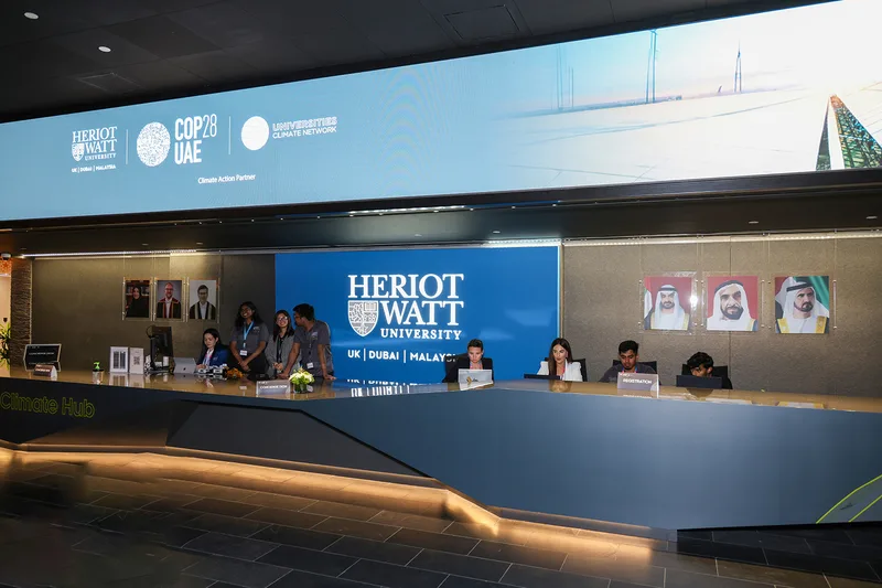 Custom lobby counter branding extending the Heriot-Watt Climate Hub identity across reception.