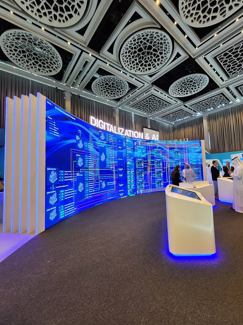 Curved exhibition environment fabricated around embedded LED screens and branded wall graphics.