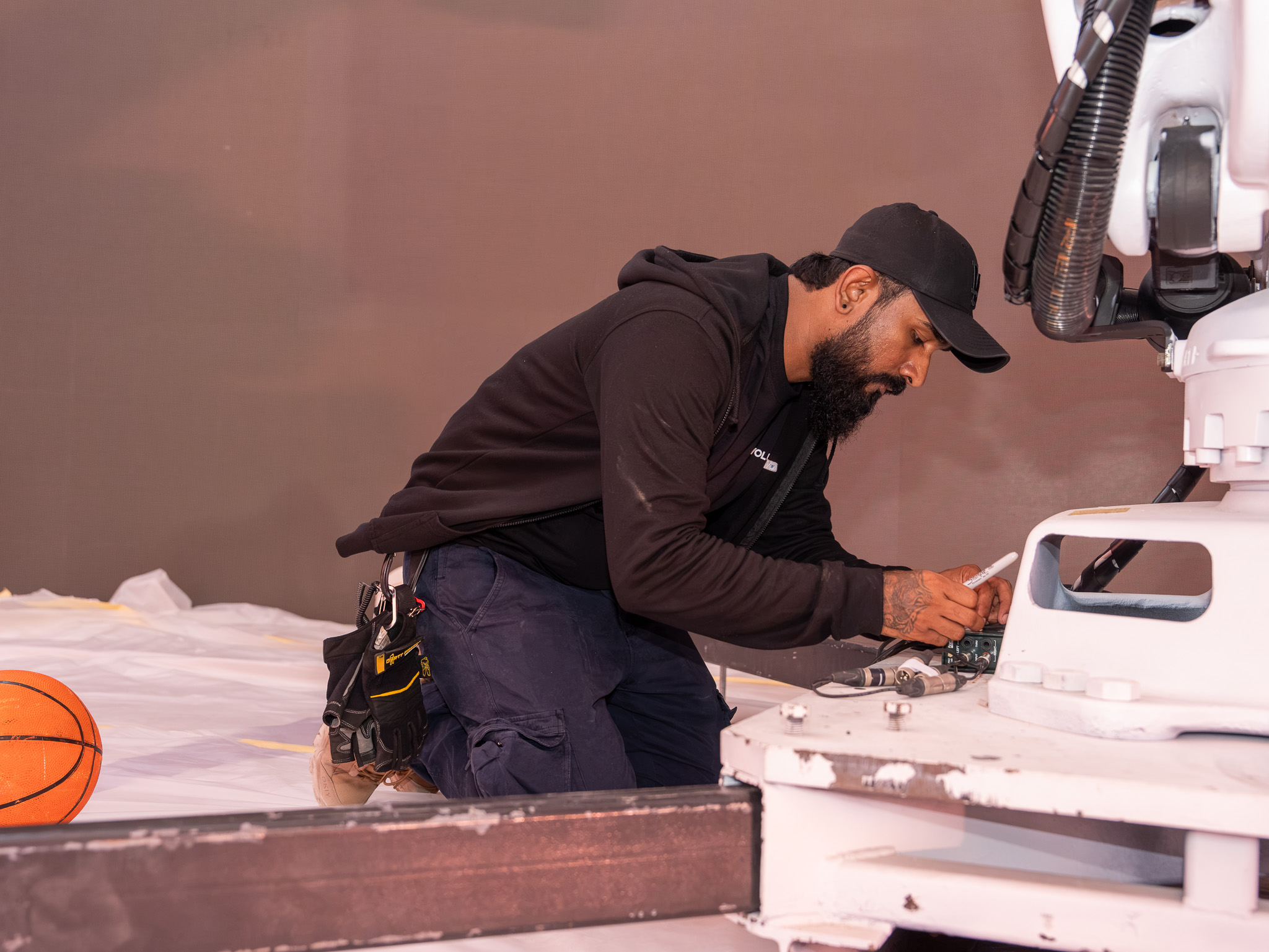 Technician servicing display equipment through a removable permanent scenic access panel.

