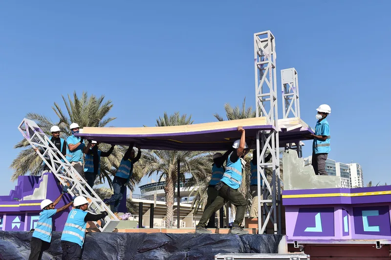 Fabrication crew installing the elevated gateway roof and side support frame on the purple Mansour Festival float