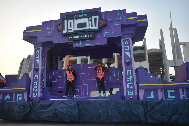 Completed Mansour Festival streetscape float with colourful building façades, palm trees and a landscaped deck.