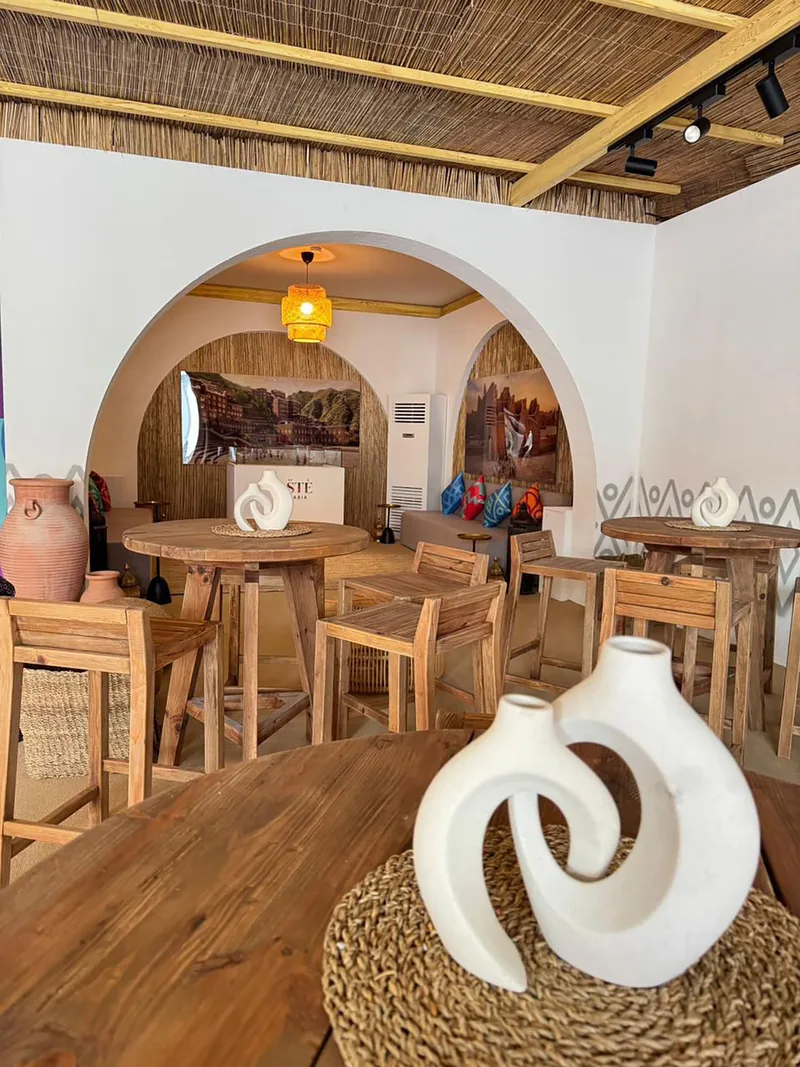 Natural solid-wood round tables arranged within the Visit Saudi main tent.