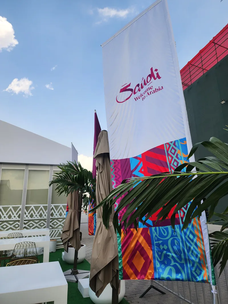 Visit Saudi branded flagpole with colourful printed graphics beside the Dubai 7s hospitality tent.