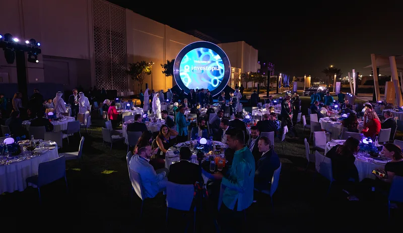 Outdoor Investopia scenic installation combining circular metalwork and integrated ambient lighting.