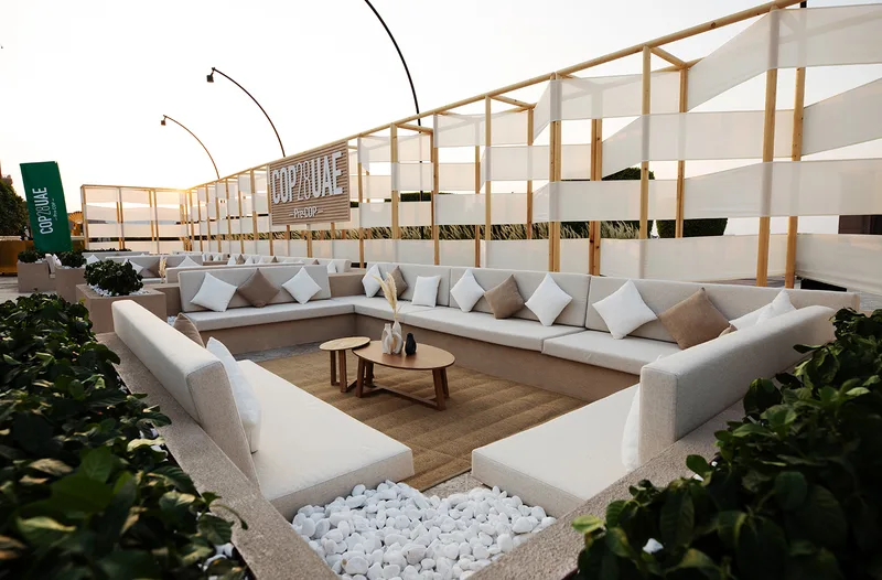 Outdoor lounge backdrop with painted three-dimensional logo and integrated scenic seating.