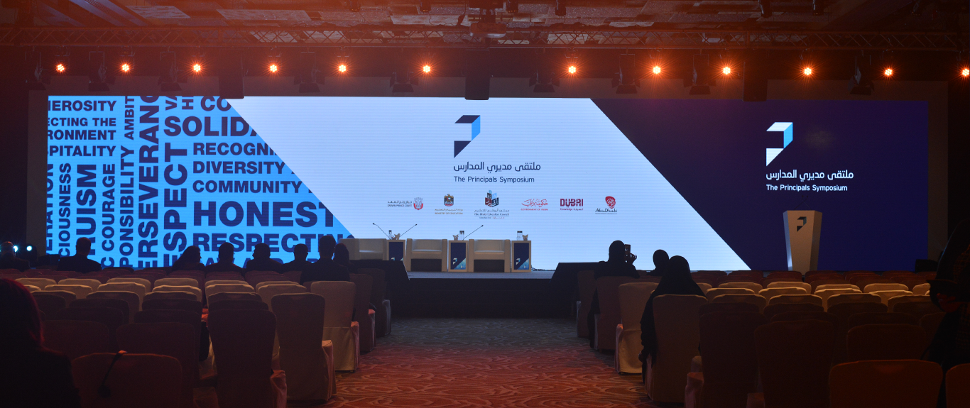 Main presentation stage with integrated LED backdrop and branded scenic environment for The Principals Symposium.