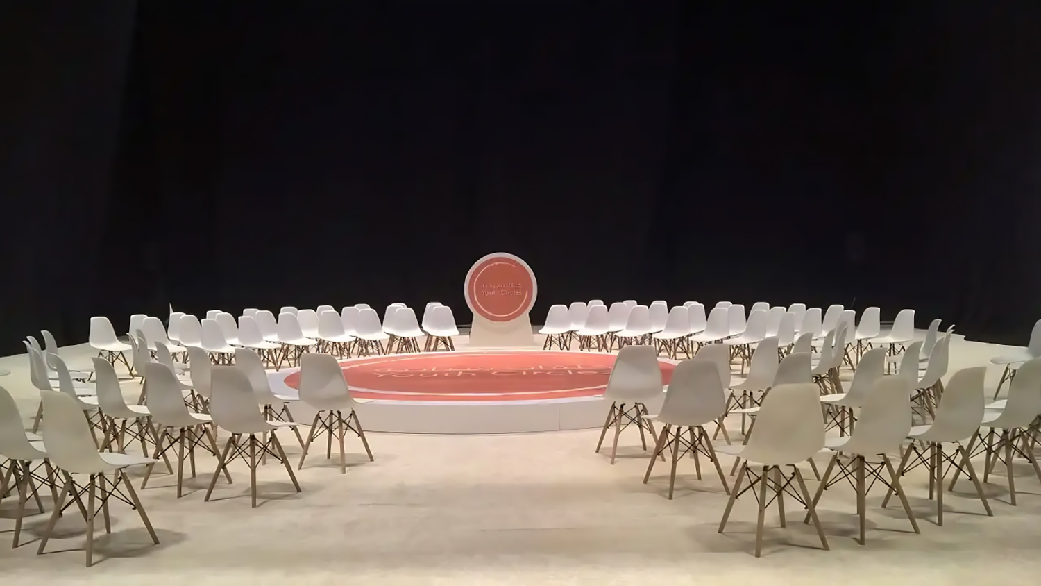 White perimeter stage construction surrounding the central orange branded floor treatment.
