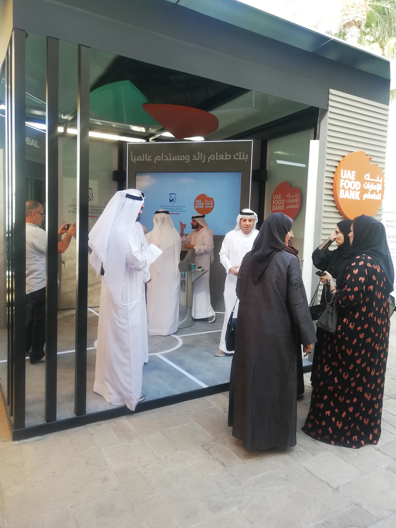 Backlit UAE Food Bank logo mounted above painted rib-panel wall detailing.