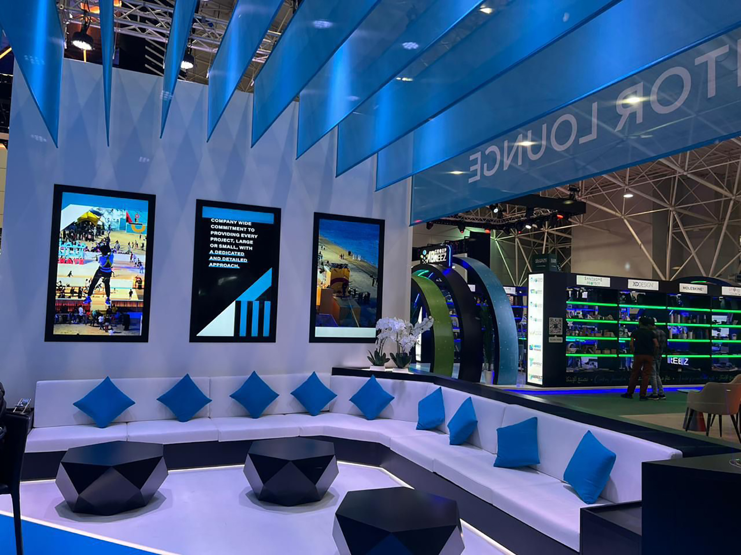 White modular scenic walls with integrated digital displays and custom exhibition seating.