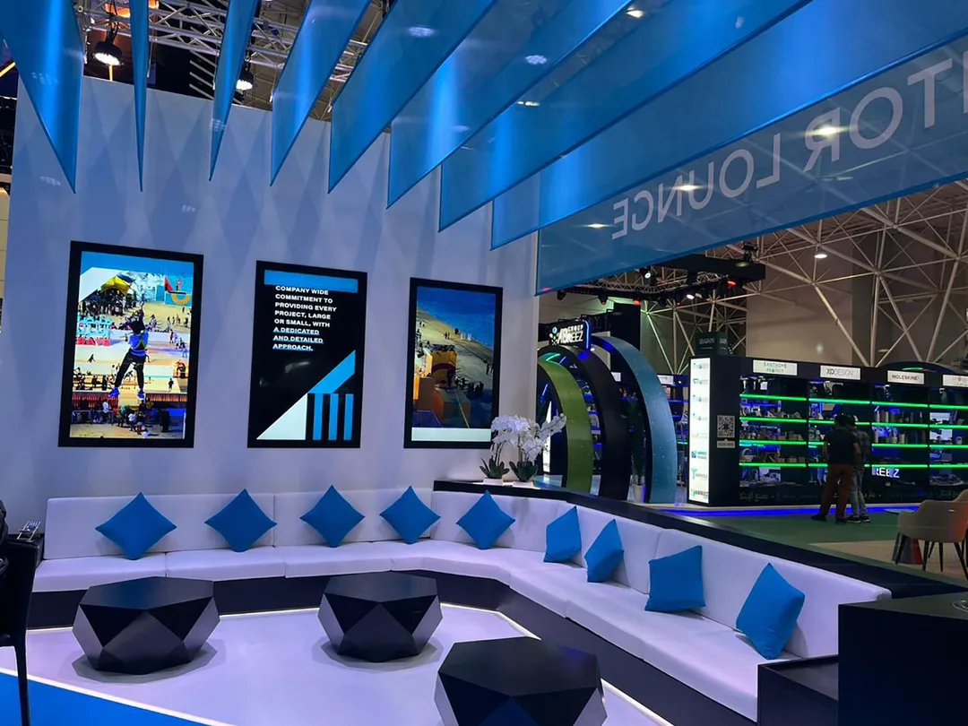 White modular scenic walls with integrated digital displays and custom exhibition seating.