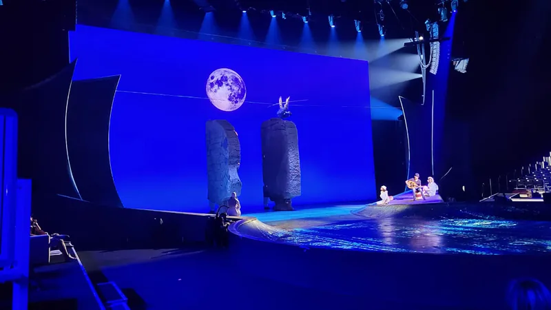 Curved scenic walls framing the central split-rock structures on the water stage.
