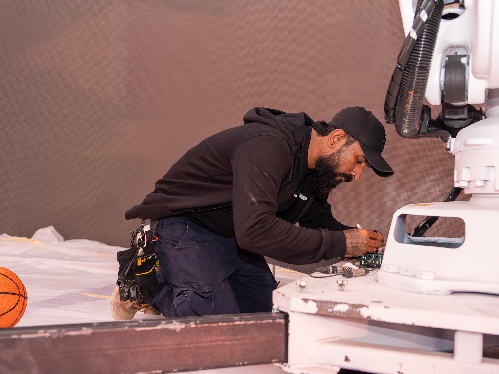 Technician reaching integrated broadcast equipment through a concealed scenic maintenance access hatch.