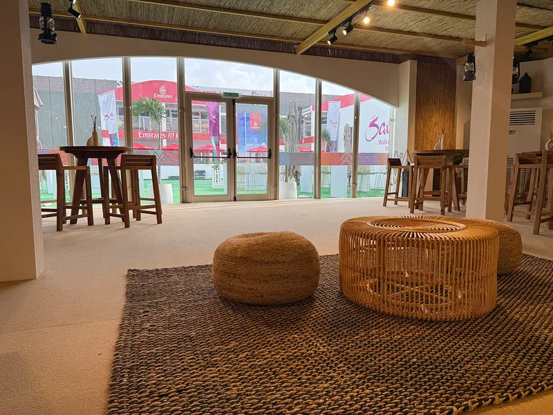 Main hospitality tent with natural timber tables, sofa seating and selected carpet.