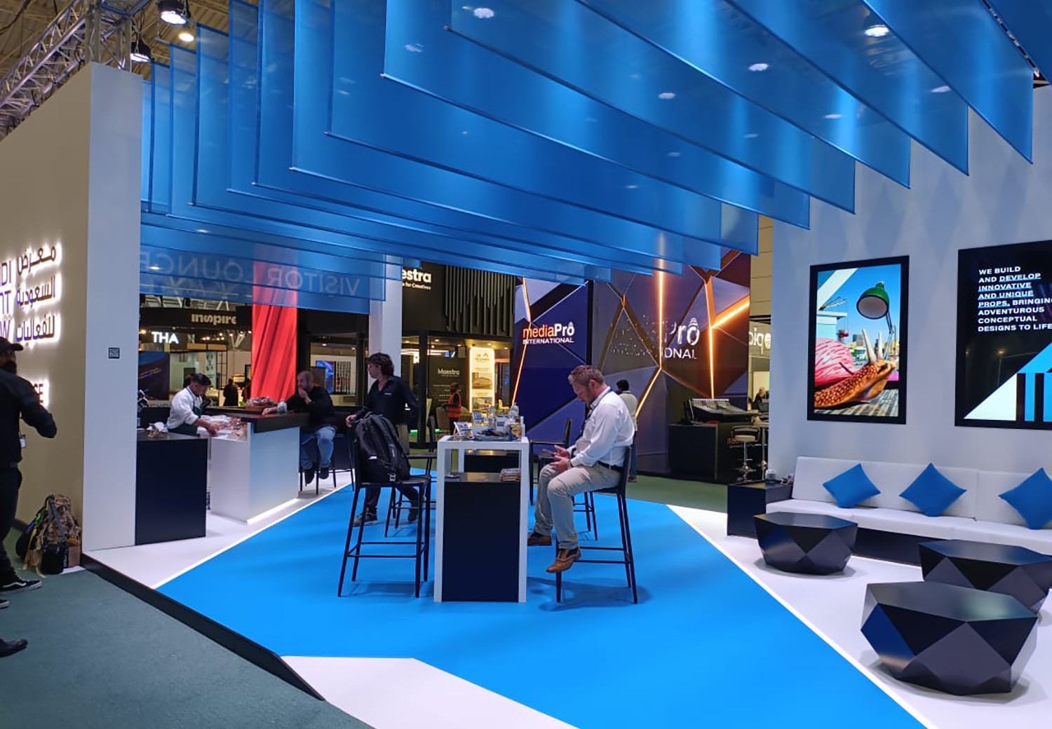 Suspended blue fabric ceiling elements supported by metal rods above the exhibition lounge.