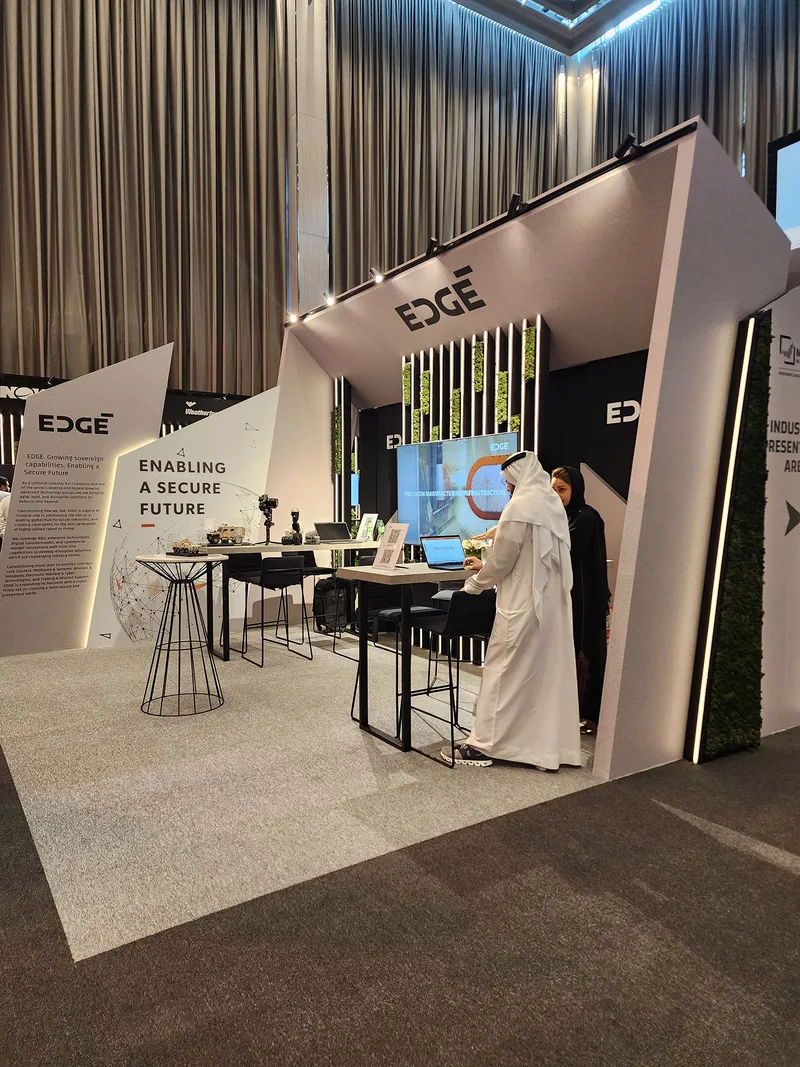Angular sponsor booth with integrated monitor frames, counters and overhead branding.