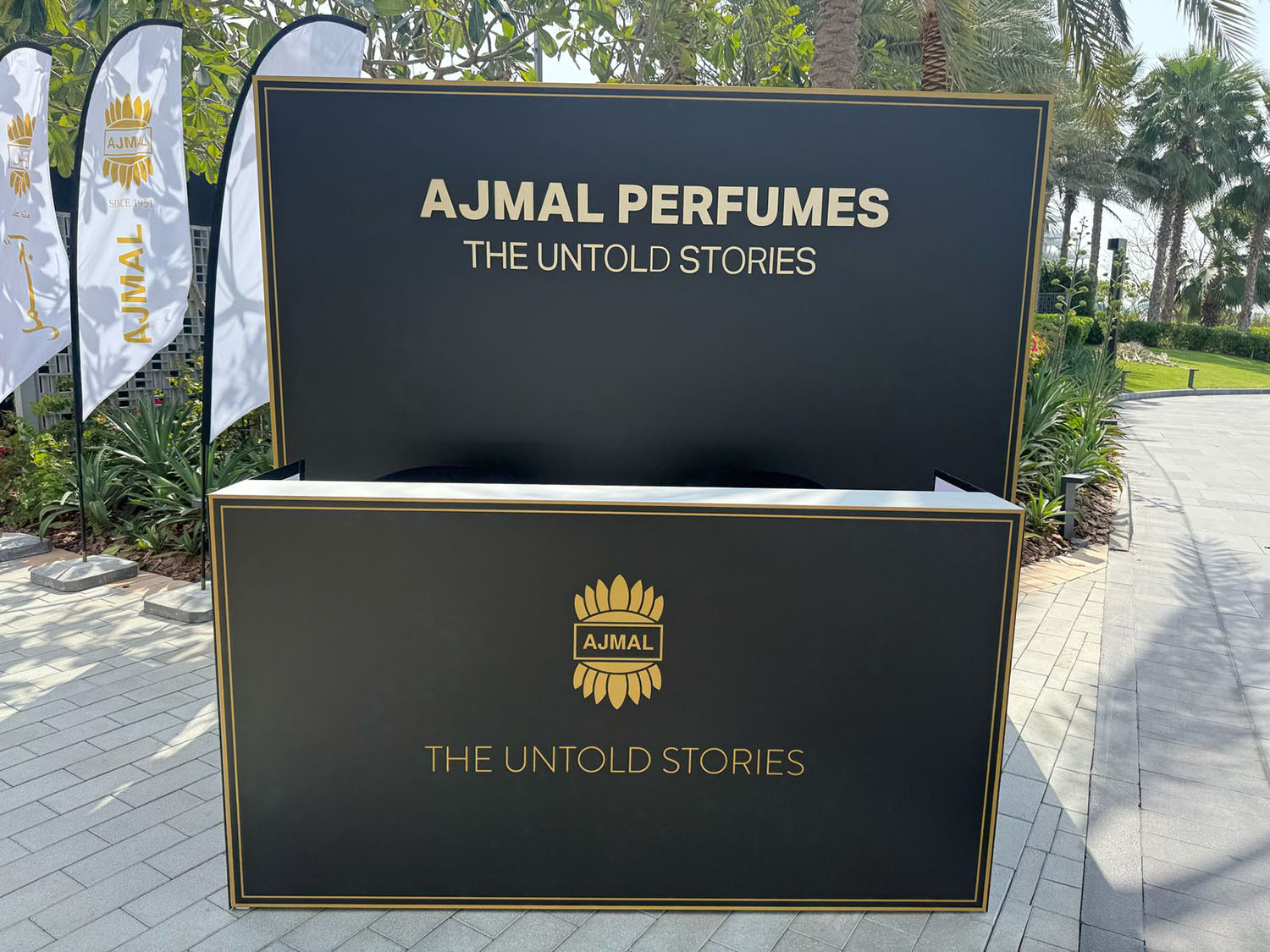 Gold vinyl Ajmal Perfumes branding applied across the black scenic registration structure.
