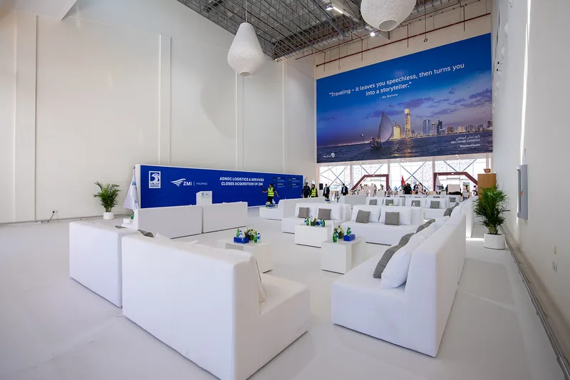 White scenic plinths and tables arranged within the branded interior setting.