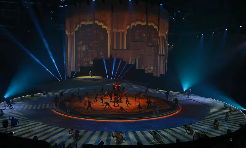Wide view of performers on the circular Terhal stage beneath suspended scenic architecture.